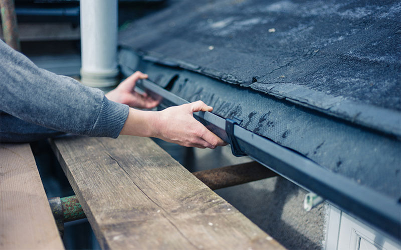 Man hands installing gutter on roof